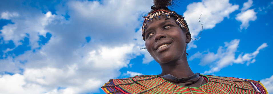 Kenyan woman with blue sky behind her wearing traditional clothing