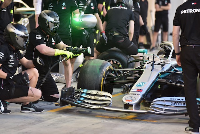 Car race pit stop workers fixing a car in black helmets and gear
