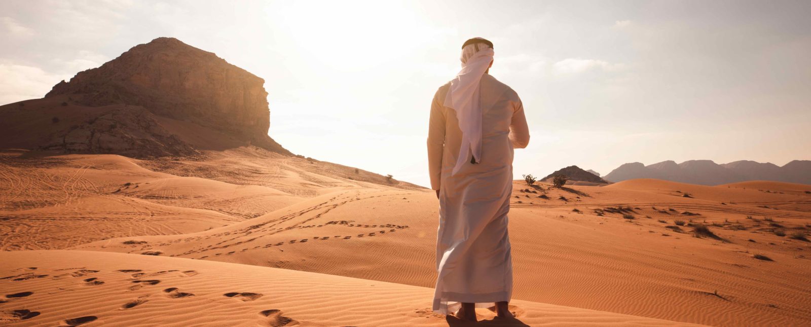 Arab man stands alone in the desert and watching the sunset.
