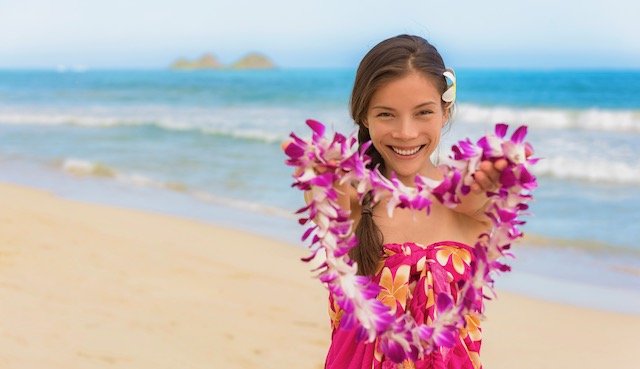 Hawaiian lei girl giving flowers as welcome to Hawaii beach travel vacation destination.