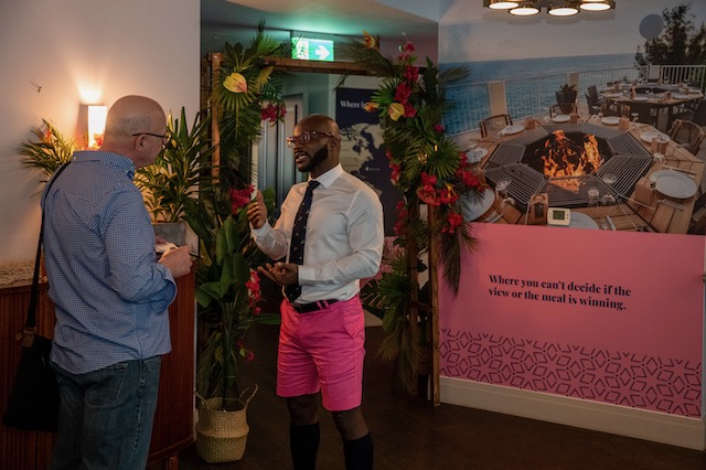 Bermuda House event. One man in pink shorts speaking to another